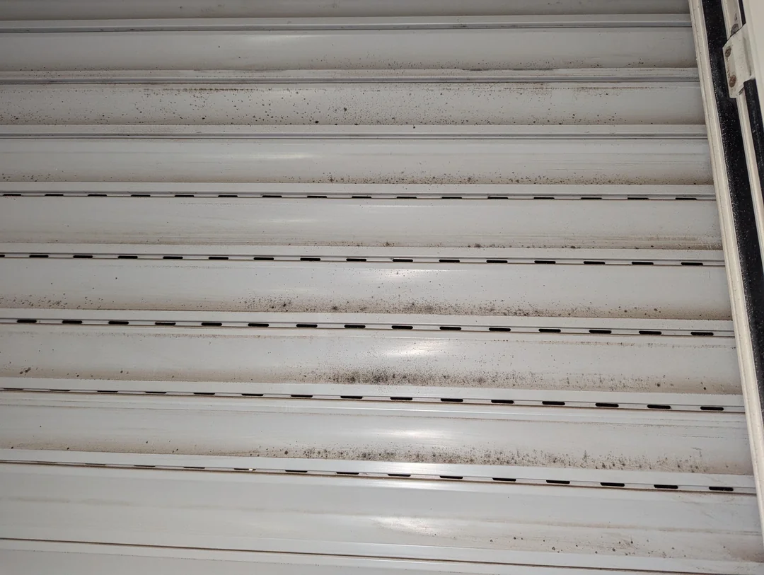 Image of a white air vent or louvered surface with visible mold and mildew spots, indicating poor indoor air quality or ventilation issues.